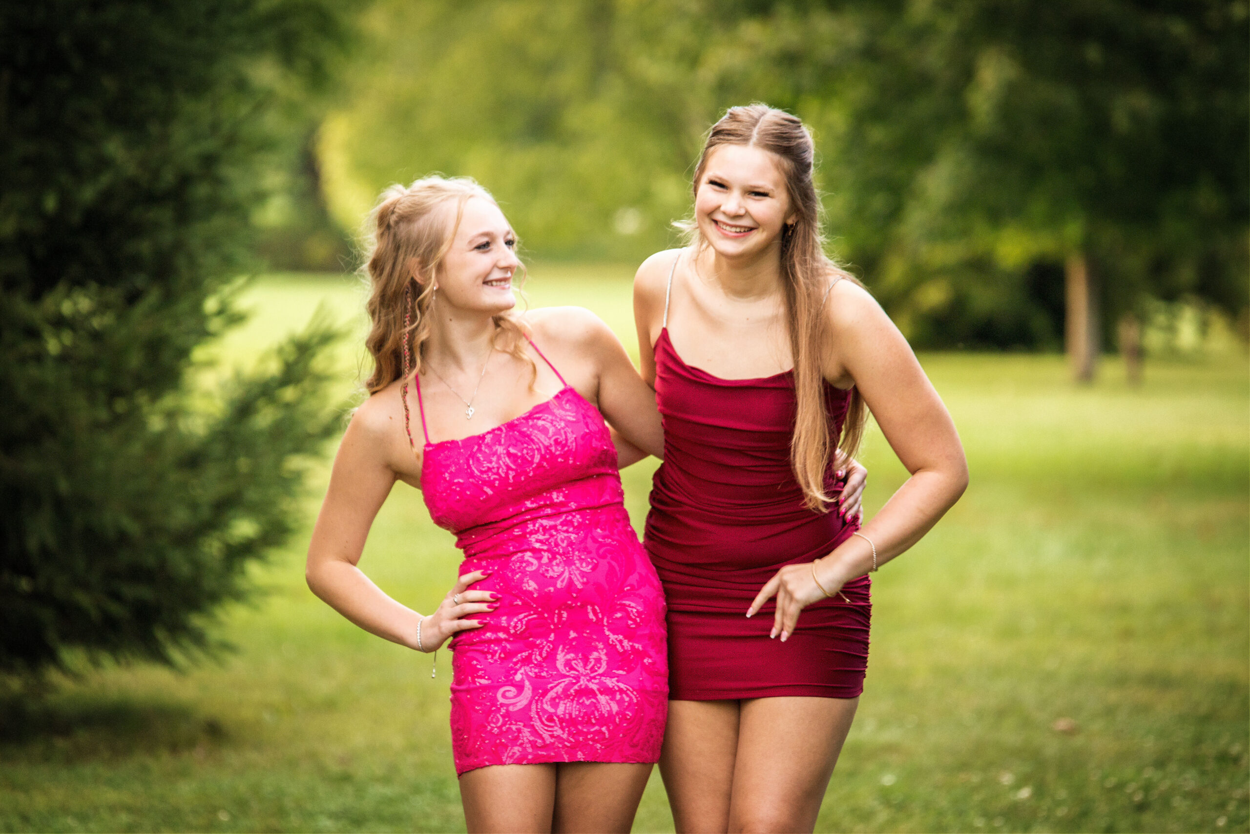 Joyful fine art portrait of two best friends in vibrant pink and red dresses, celebrating their friendship.