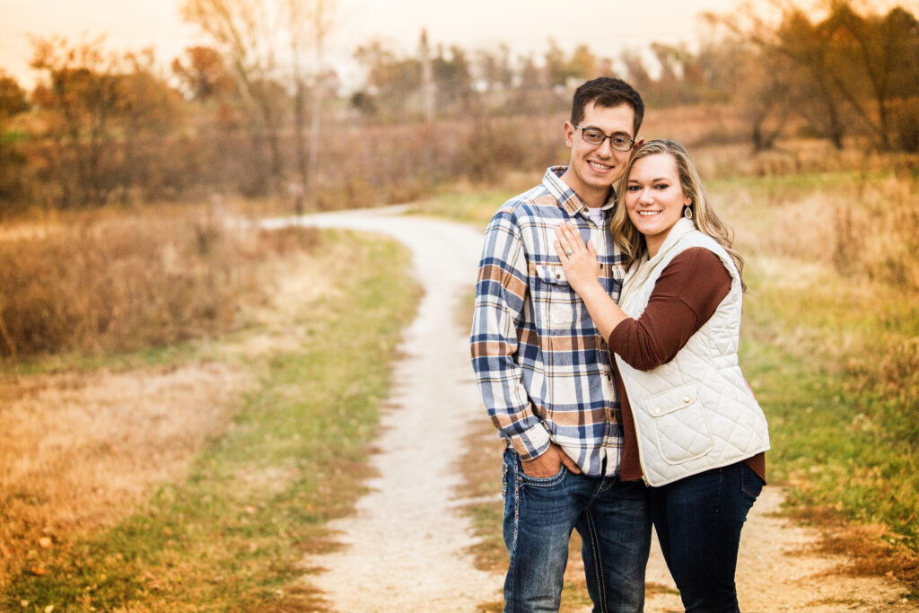 Warm fine art portrait of an engaged couple on a winding dirt road during autumn, showcasing their genuine connection.