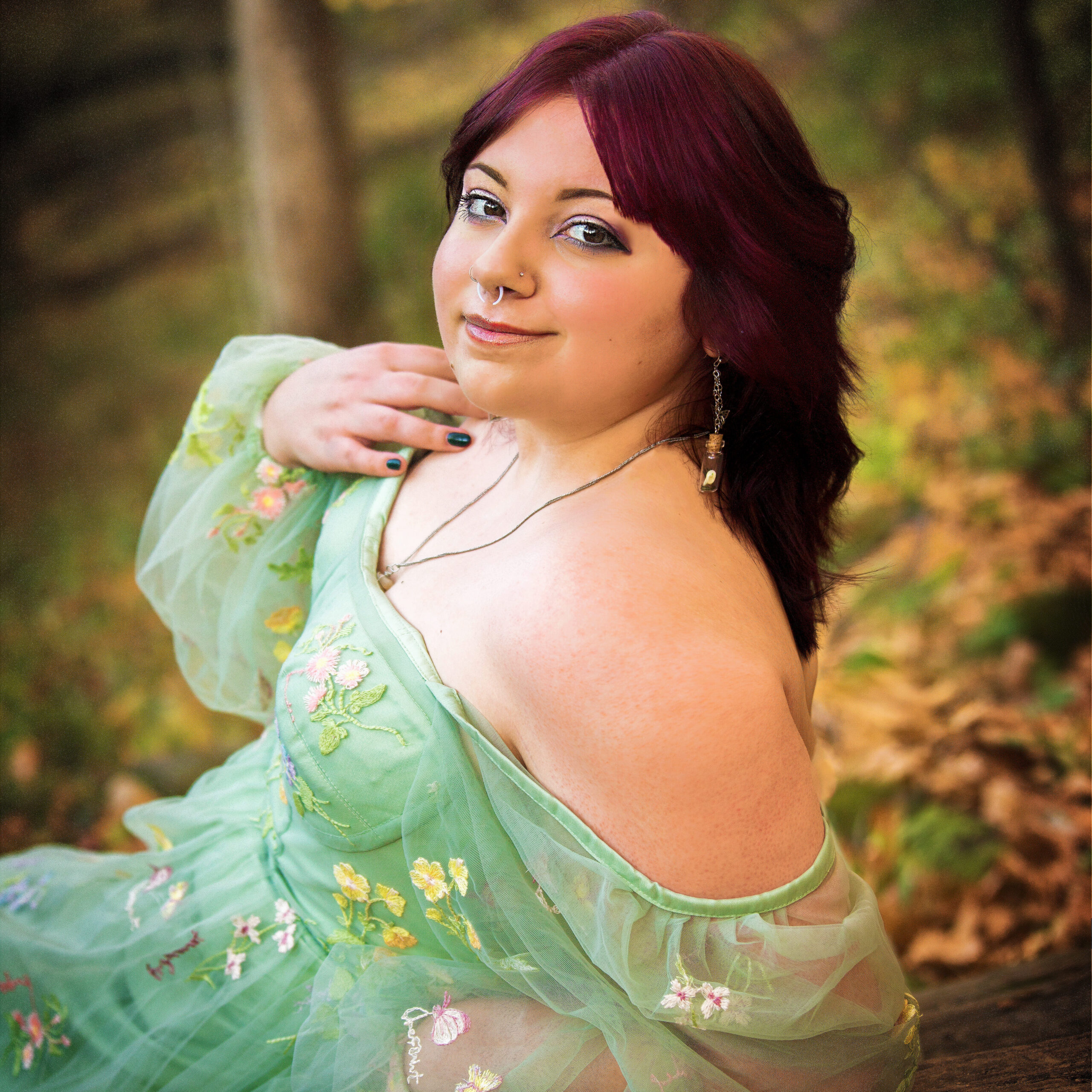 Ethereal fine art portrait of a woman in a sage green embroidered gown in a woodland setting.